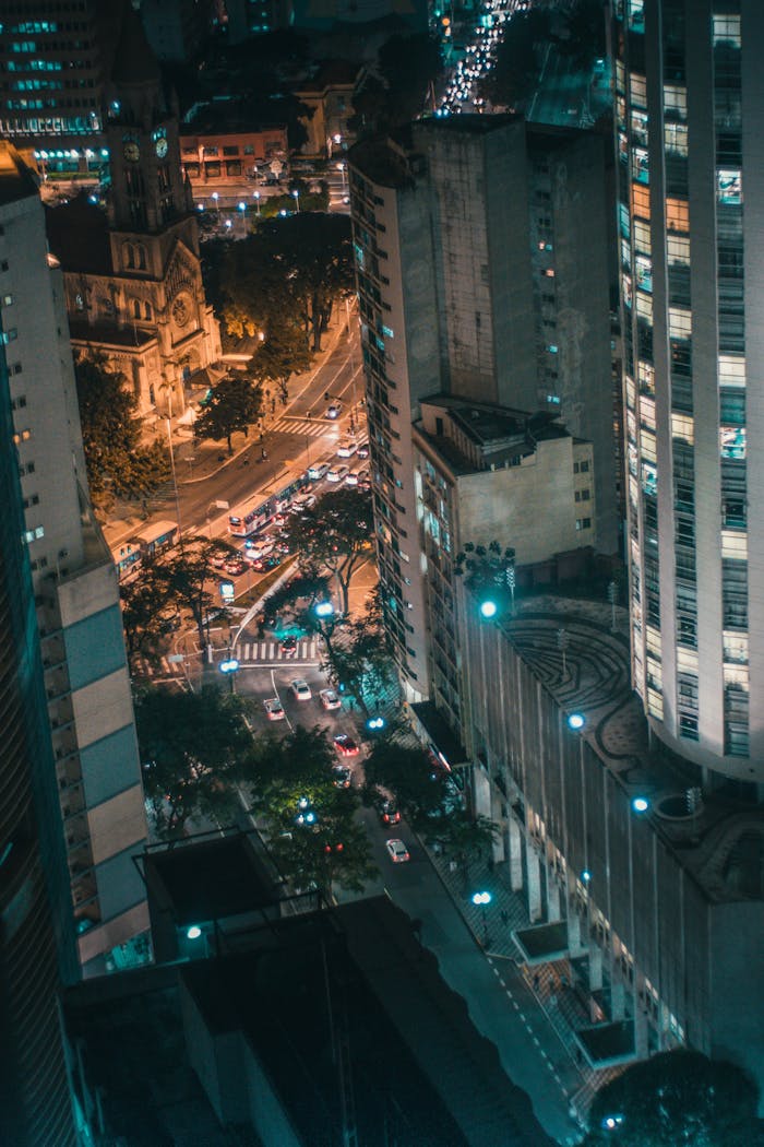 A dramatic aerial view of a city with illuminated streets and modern skyscrapers at night.